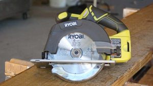 Ryobi compact circular saw with blade and accessories laid out on workbench