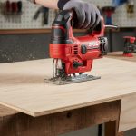 Battery-powered cordless jigsaw cutting smooth curve in plywood sheet