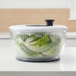 OXO salad spinner on a kitchen counter spinning fresh greens.